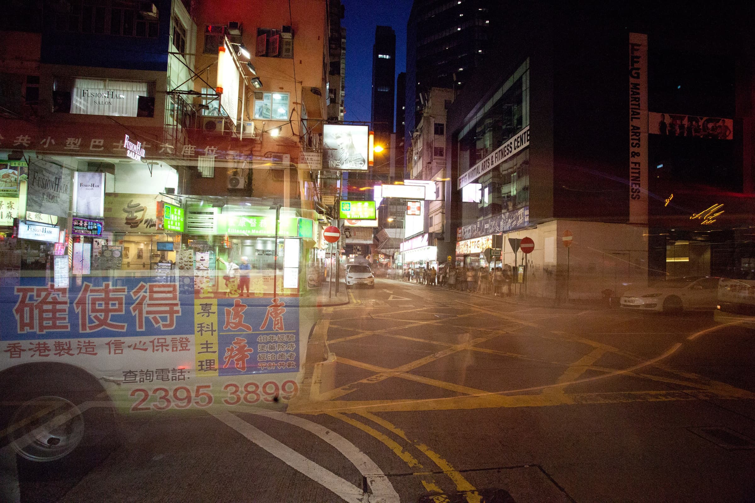 City street at night with neon signs and a passing bus