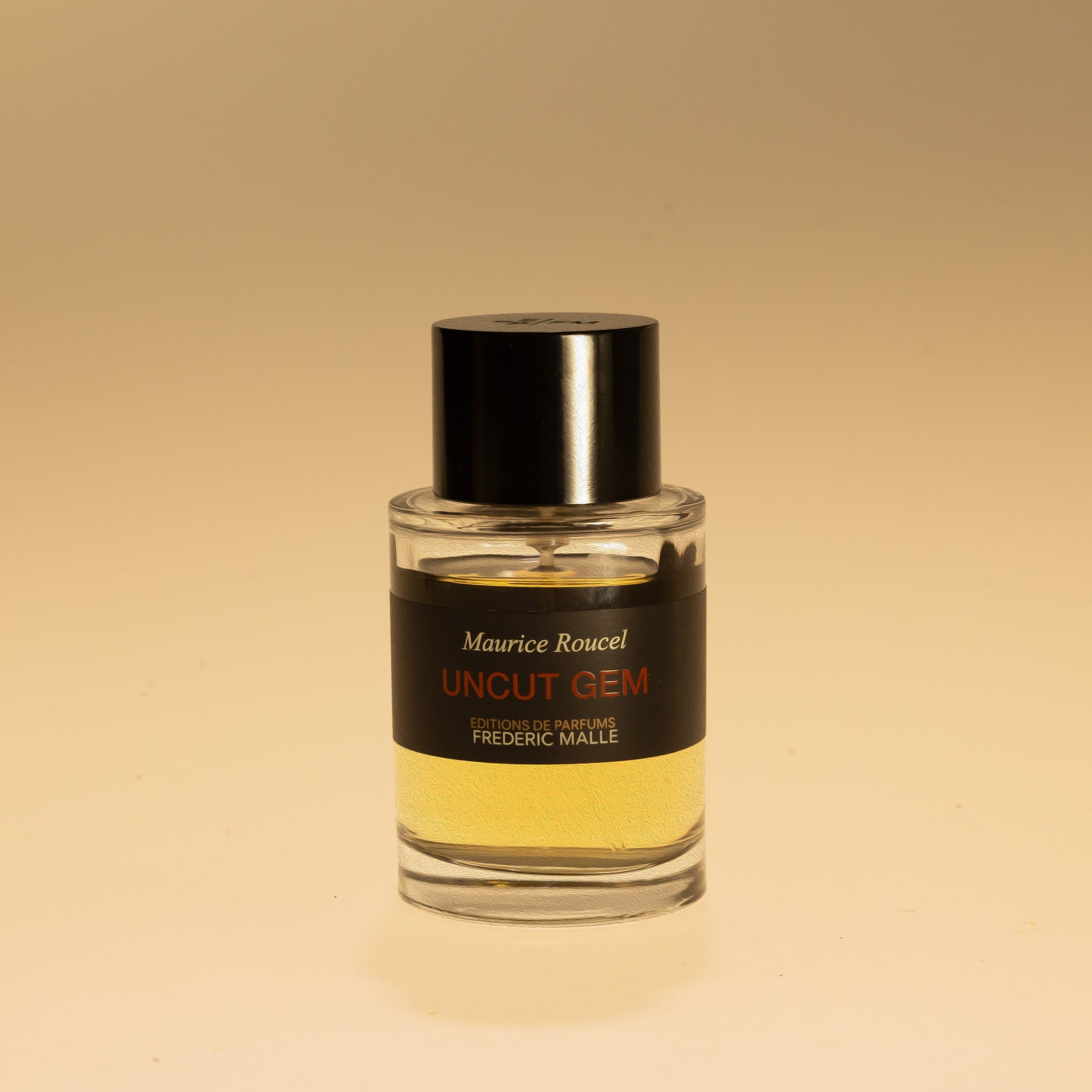 Glass perfume bottle with a black cap against warm yellow light
